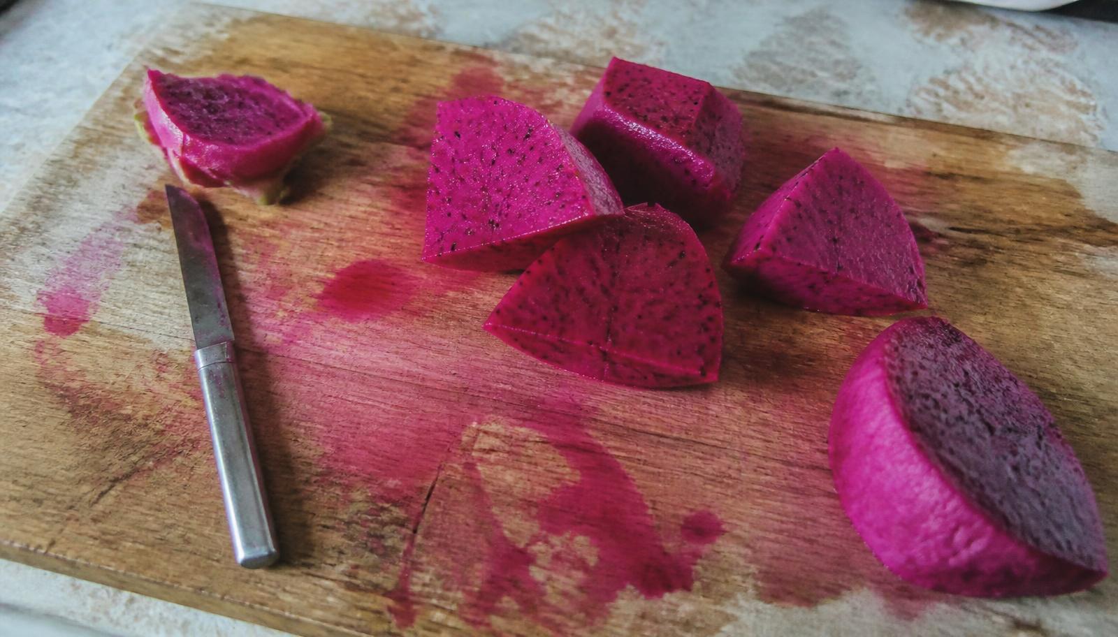 Halved pink dragon fruit sliced on a wooden board